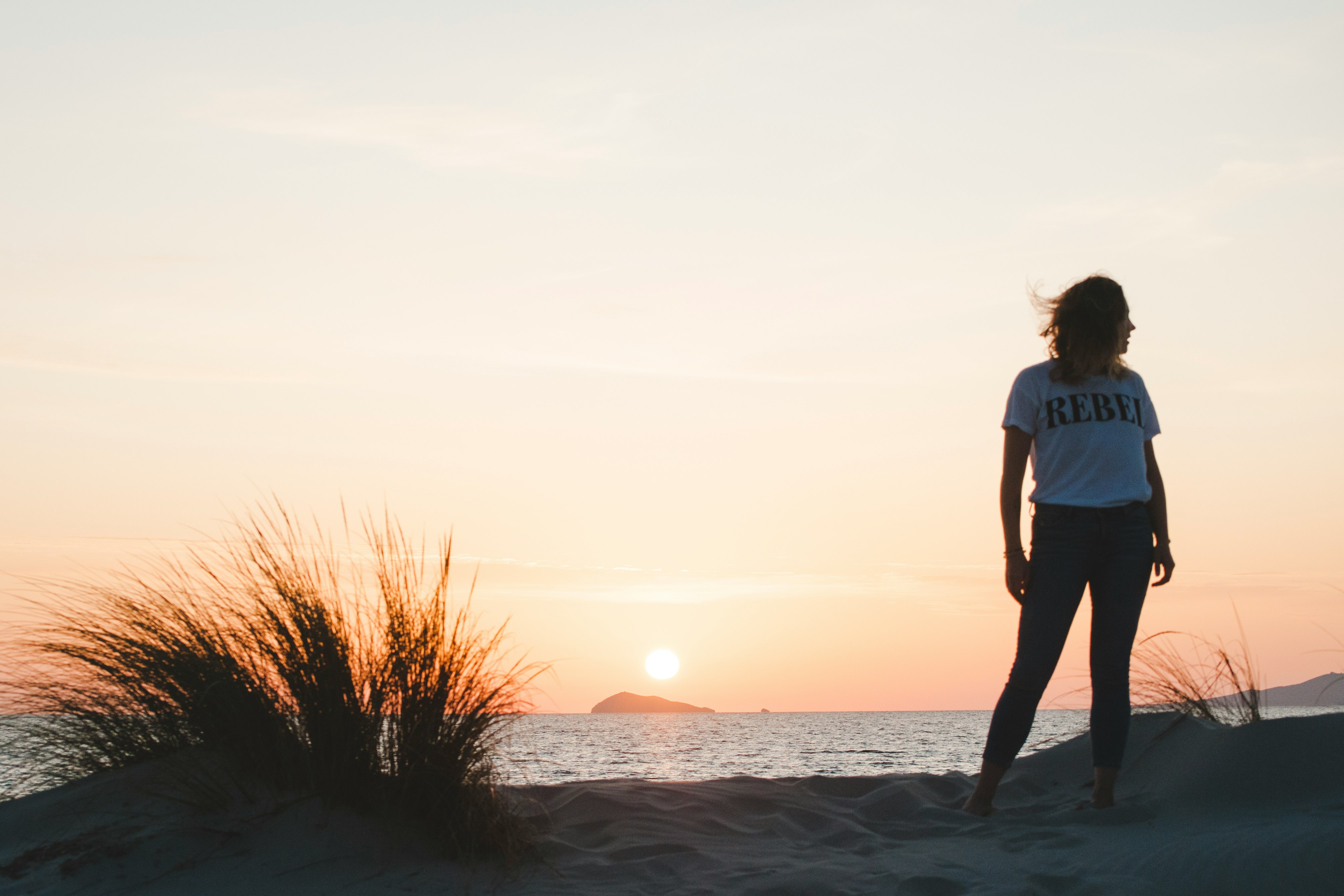 woman in blue t-shirt standing on seashore during sunset